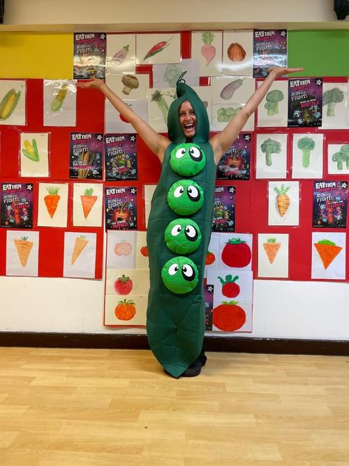 Our Catering Manager Natalie in costume with pictures from our children of some of the vegetables they have been tasting